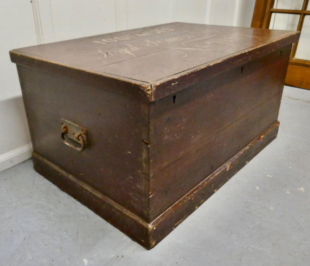 A 19th-century dark stained pine lodge chest featuring white painted lettering on the hinged top lid and a solid plinth base. View V