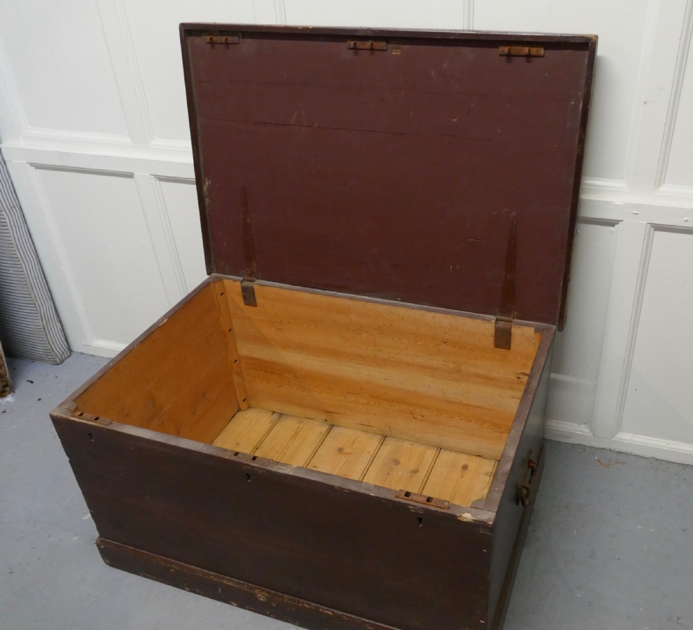 A 19th-century dark stained pine lodge chest featuring white painted lettering on the hinged top lid and a solid plinth base. View VIII