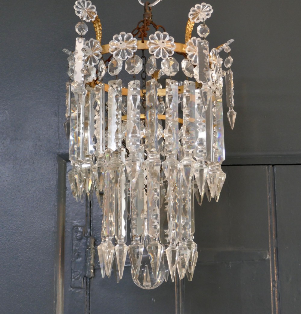 A two-tier waterfall chandelier featuring clear cut-crystal prism drops hung from a gilded metal band with rosette details.
