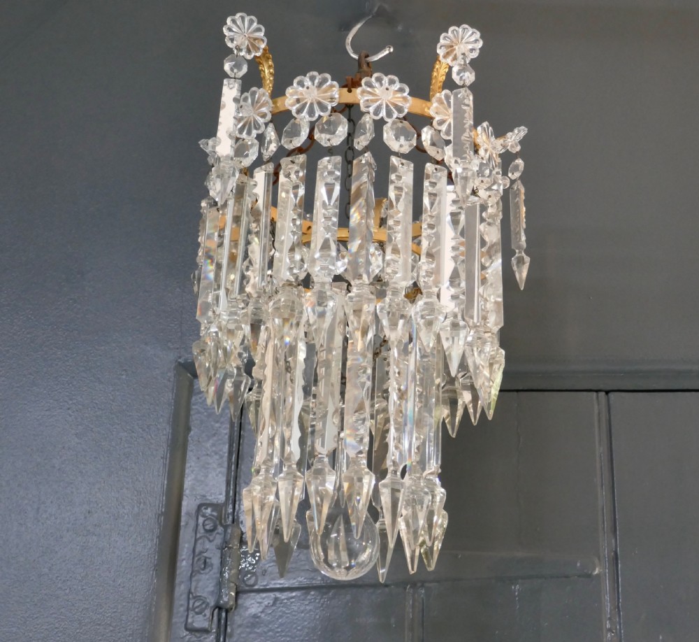 A two-tier waterfall chandelier featuring clear cut-crystal prism drops hung from a gilded metal band with rosette details. View II