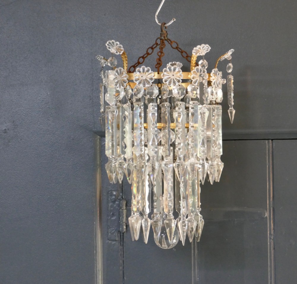 A two-tier waterfall chandelier featuring clear cut-crystal prism drops hung from a gilded metal band with rosette details. View III