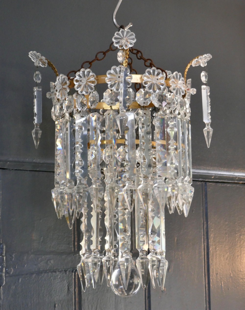 A two-tier waterfall chandelier featuring clear cut-crystal prism drops hung from a gilded metal band with rosette details. View VI