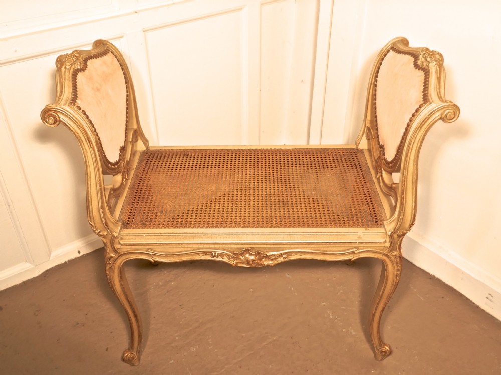 An antique French giltwood window seat featuring raised dusky pink velvet ends with studding, a cane seat, and curved cabriole legs. View II