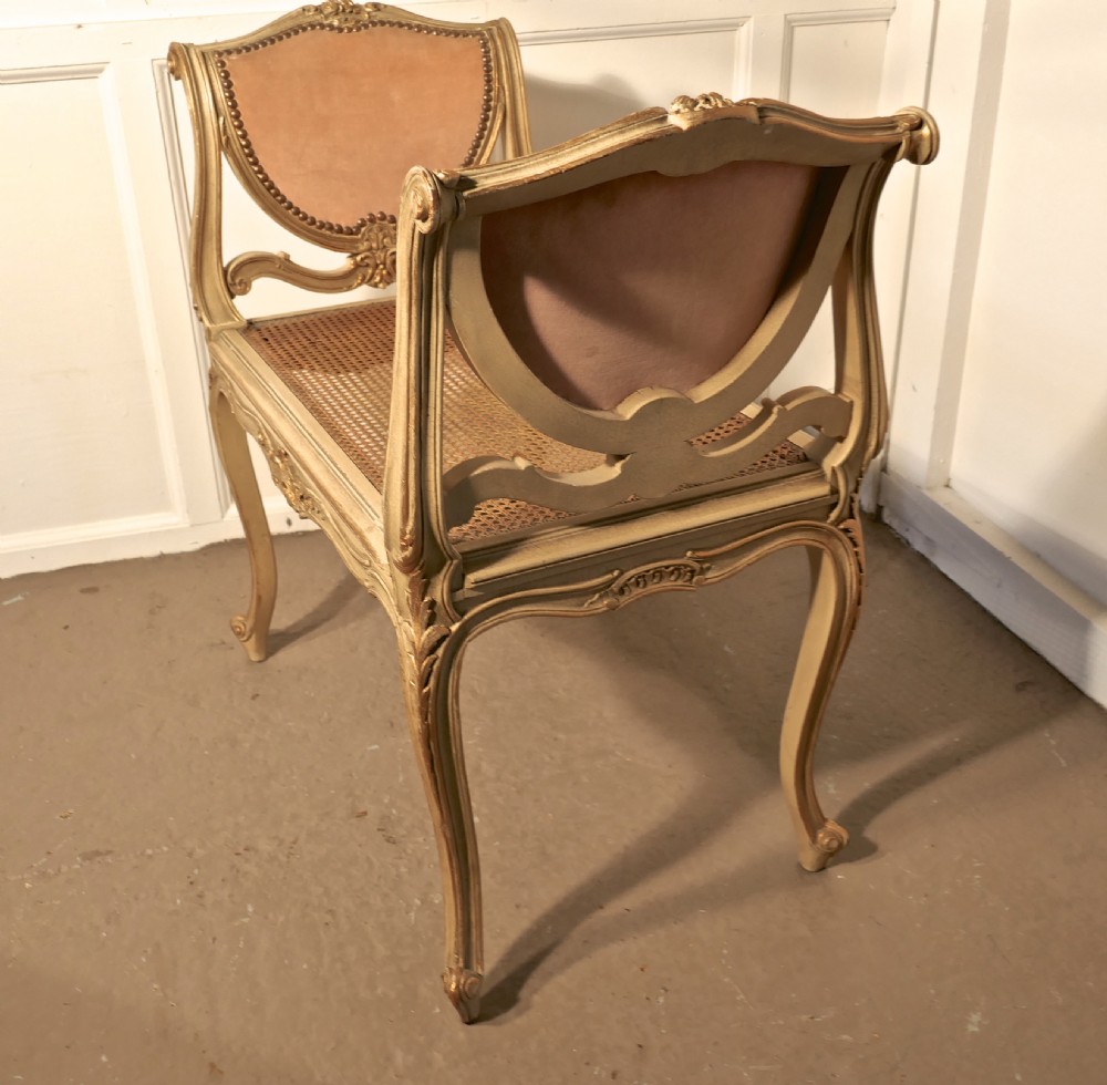 An antique French giltwood window seat featuring raised dusky pink velvet ends with studding, a cane seat, and curved cabriole legs. View V