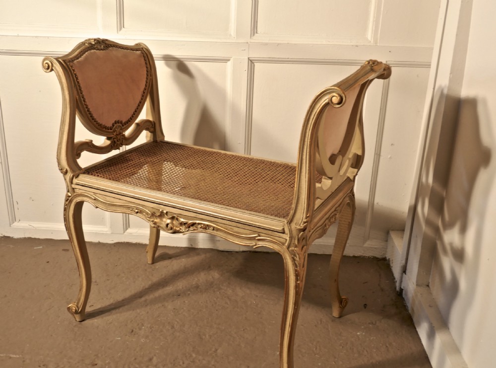An antique French giltwood window seat featuring raised dusky pink velvet ends with studding, a cane seat, and curved cabriole legs. View VI