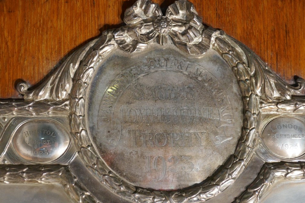 A shield-shaped oak wall plaque featuring a silver-plated relief of the winged goddess Nike surrounded by laurel motifs and small engraved oval shields. View III
