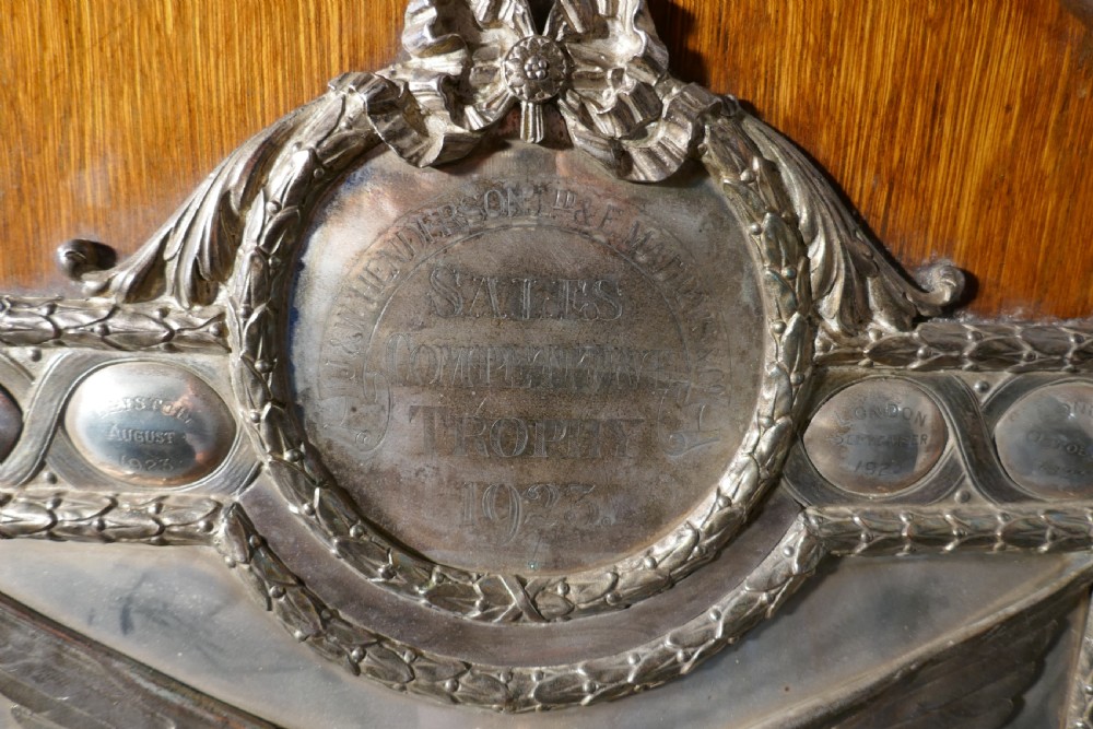 A shield-shaped oak wall plaque featuring a silver-plated relief of the winged goddess Nike surrounded by laurel motifs and small engraved oval shields. View V