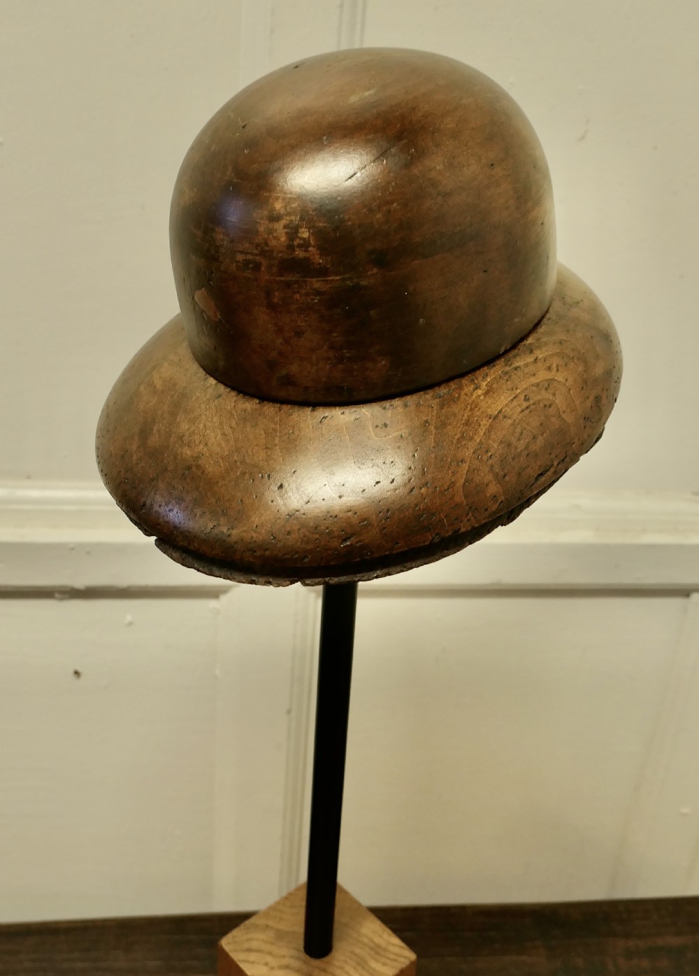 An antique French fruitwood hat display stand featuring a carved wooden crown form mounted on a black metal shaft with a wooden base. View II