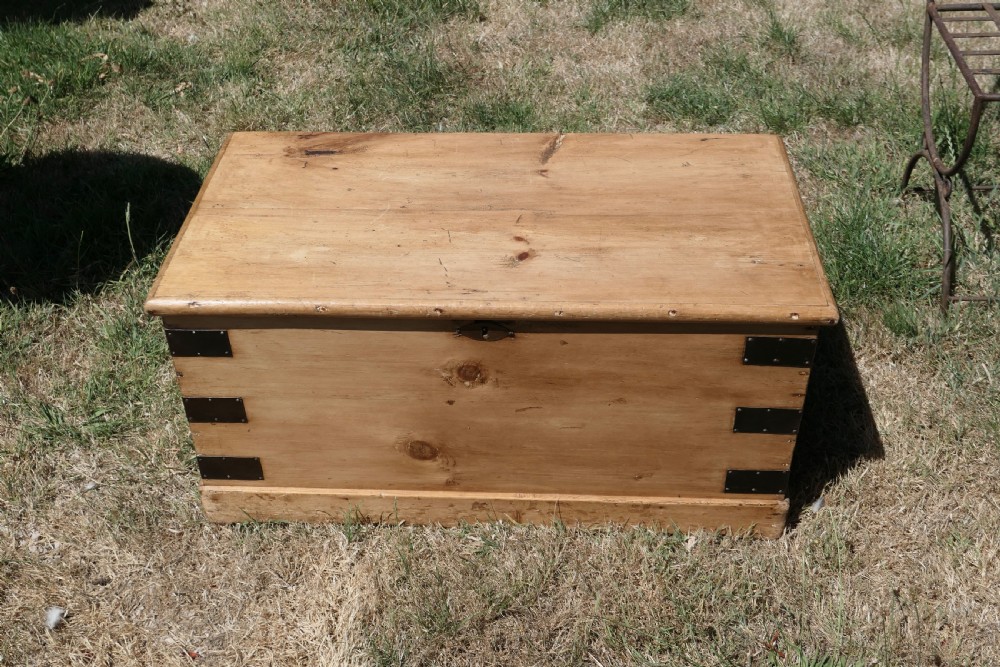 A rectangular stripped pine blanket box with dark iron corner brackets, a keyhole escutcheon, and a flat hinged lid. View II