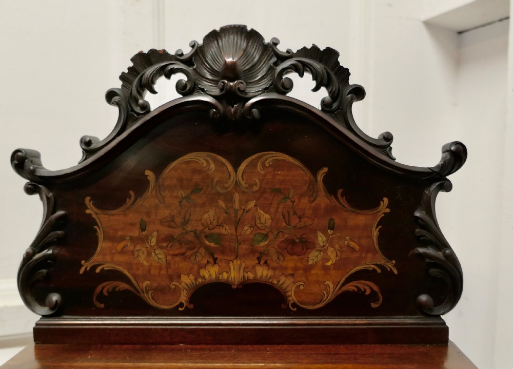 A late nineteenth-century dark wood coal purdonium featuring decorative floral marquetry inlay, carved scroll cresting, and a brass drop handle. View II