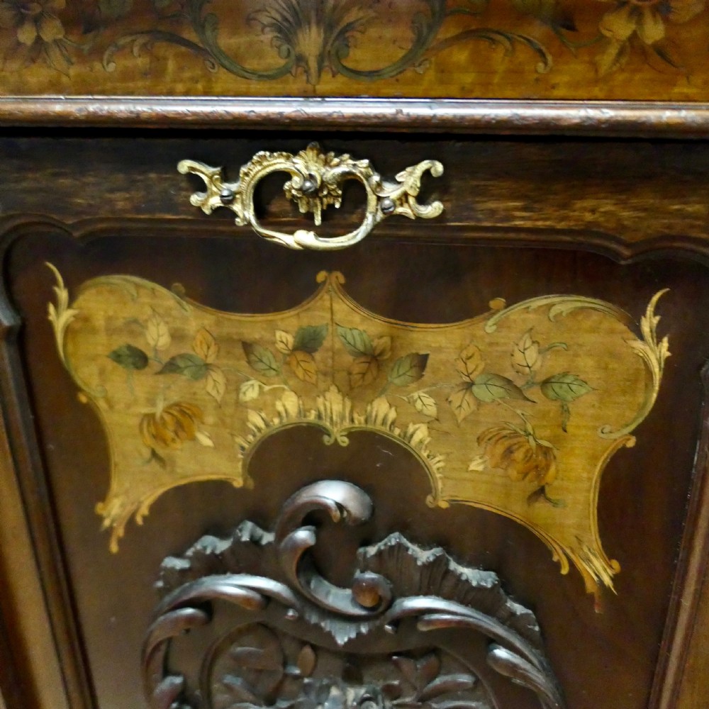 A late nineteenth-century dark wood coal purdonium featuring decorative floral marquetry inlay, carved scroll cresting, and a brass drop handle. View III