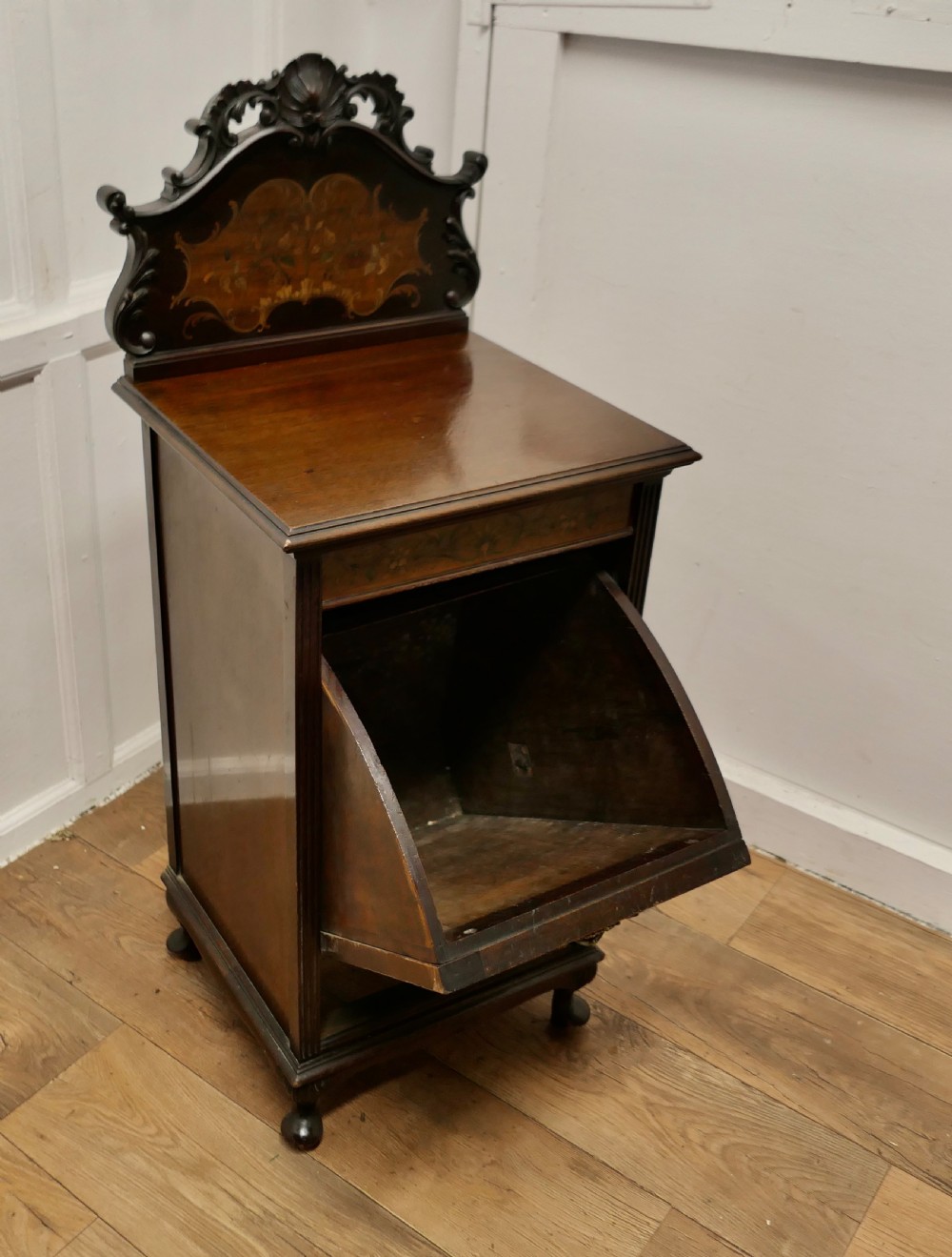 A late nineteenth-century dark wood coal purdonium featuring decorative floral marquetry inlay, carved scroll cresting, and a brass drop handle. View VI