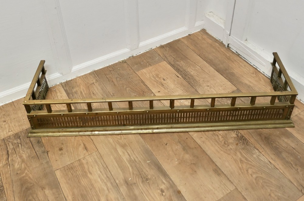 A Victorian solid brass fireplace fender featuring a slotted lower gallery, stud detailing, and an elevated top rail. View III