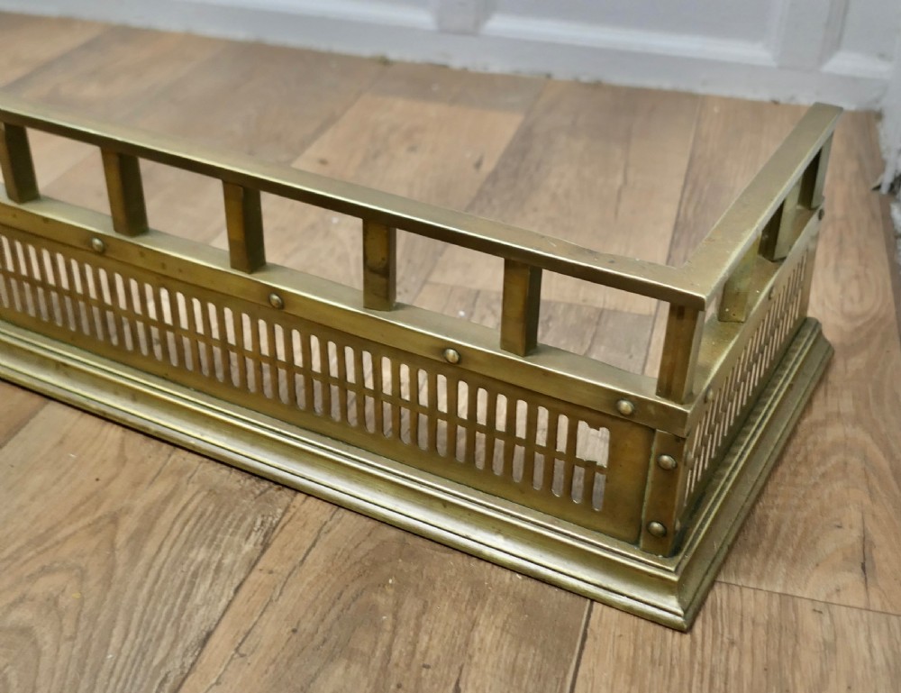A Victorian solid brass fireplace fender featuring a slotted lower gallery, stud detailing, and an elevated top rail. View V