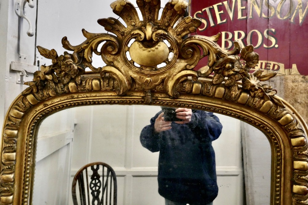 A large 19th-century French arched giltwood wall mirror featuring an ornate carved cresting pediment and beaded border. View III
