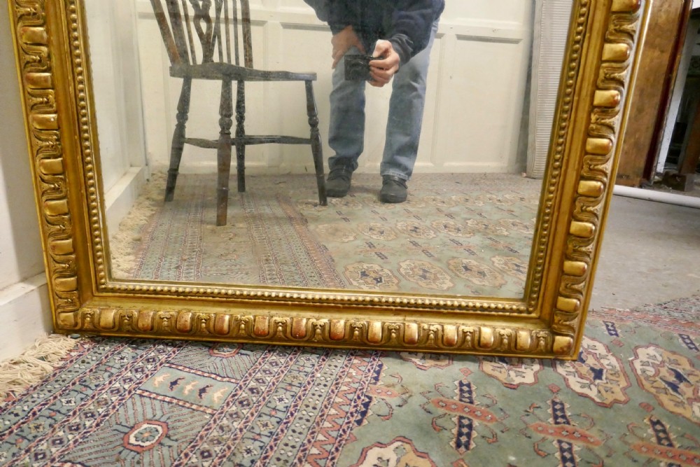 A large 19th-century French arched giltwood wall mirror featuring an ornate carved cresting pediment and beaded border. View V