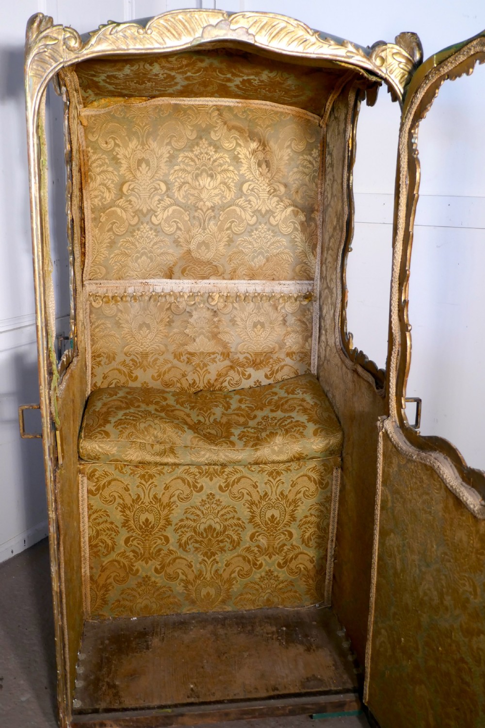 A 19th-century green painted and giltwood Italian sedan chair featuring hand-carved scrollwork, window openings, gold fabric lining, and wooden carrying poles. View VII