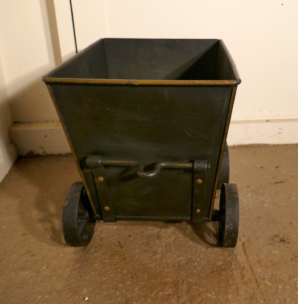 A dark iron coal scuttle shaped like a miniature wagon with four spoked wheels and a rear handle. View IV