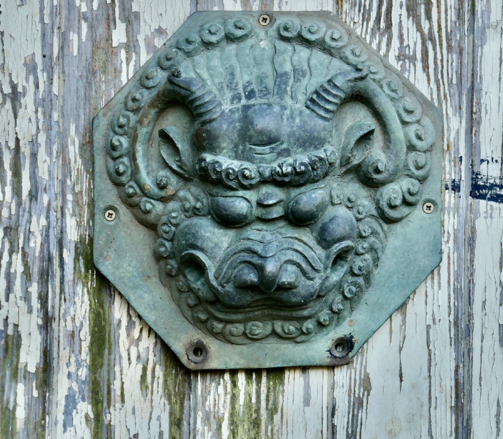A pair of octagonal patinated bronze Chinese door plates featuring relief carvings of guardian lion heads with curled manes and horns. View II