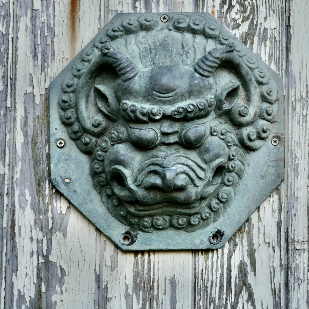 A pair of octagonal patinated bronze Chinese door plates featuring relief carvings of guardian lion heads with curled manes and horns. View III