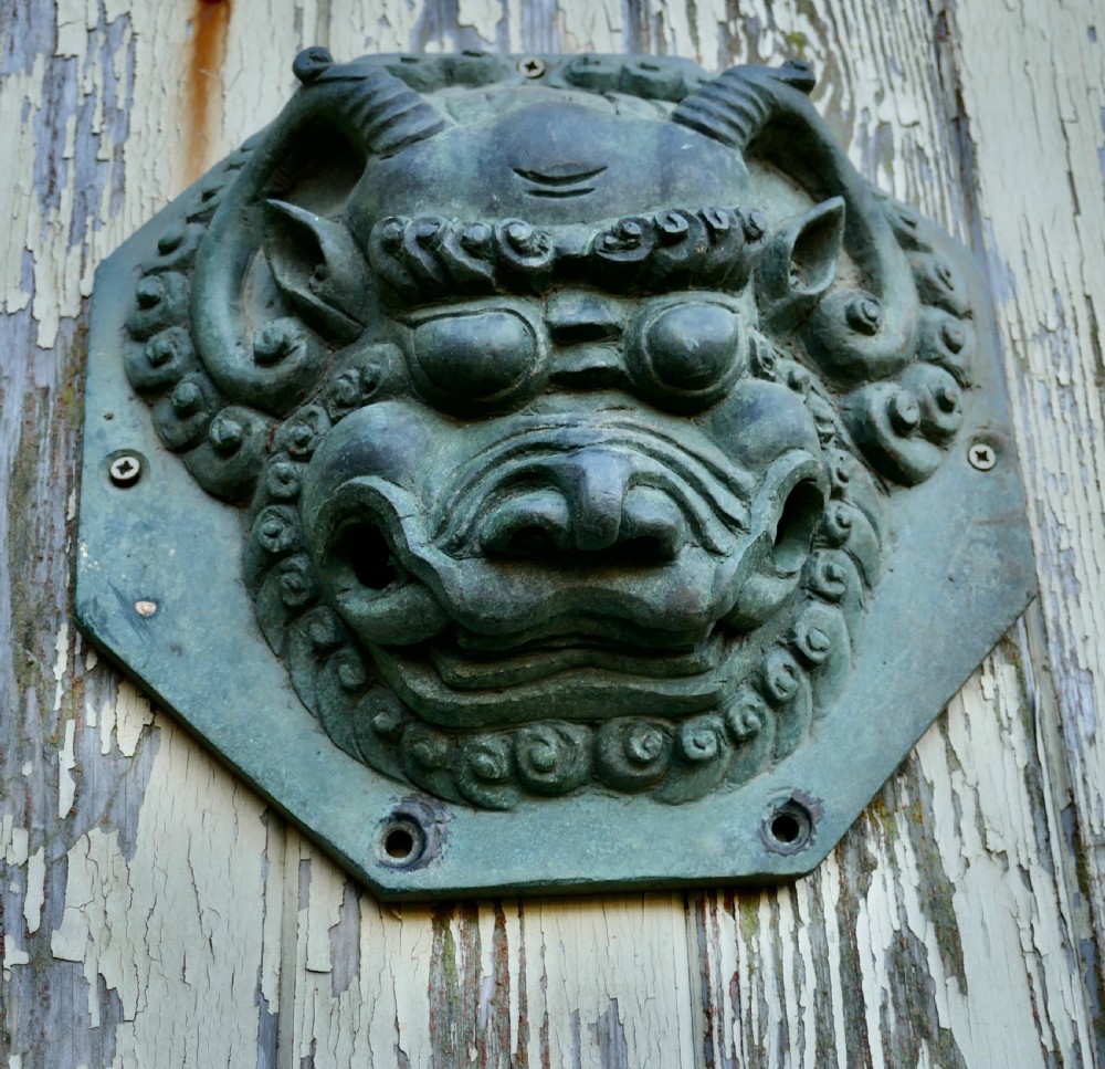 A pair of octagonal patinated bronze Chinese door plates featuring relief carvings of guardian lion heads with curled manes and horns. View IV