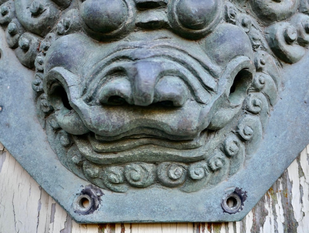 A pair of octagonal patinated bronze Chinese door plates featuring relief carvings of guardian lion heads with curled manes and horns. View VII