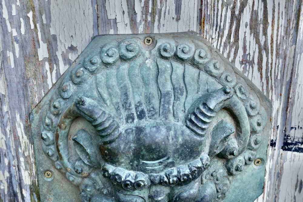 A pair of octagonal patinated bronze Chinese door plates featuring relief carvings of guardian lion heads with curled manes and horns. View VIII