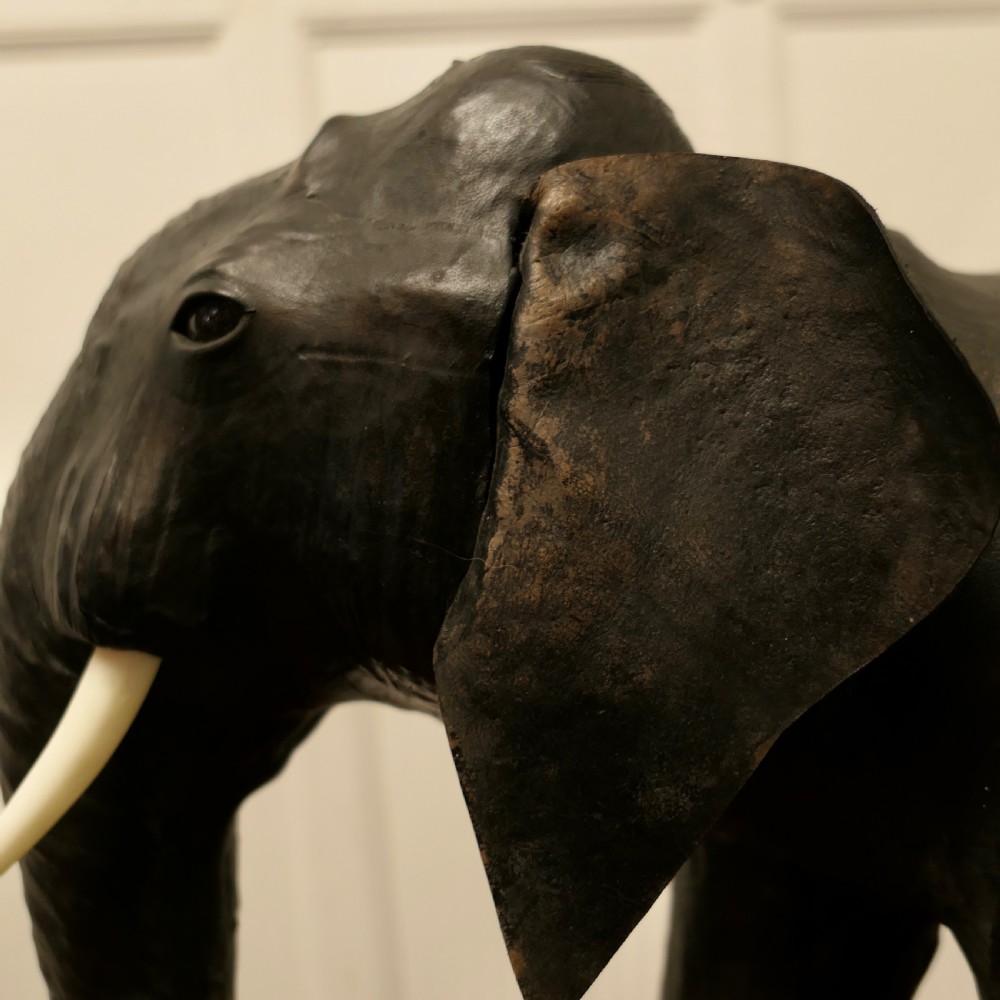 A dark brown moulded leather model of a standing bull elephant with realistic skin texture and light-coloured tusks. View VI