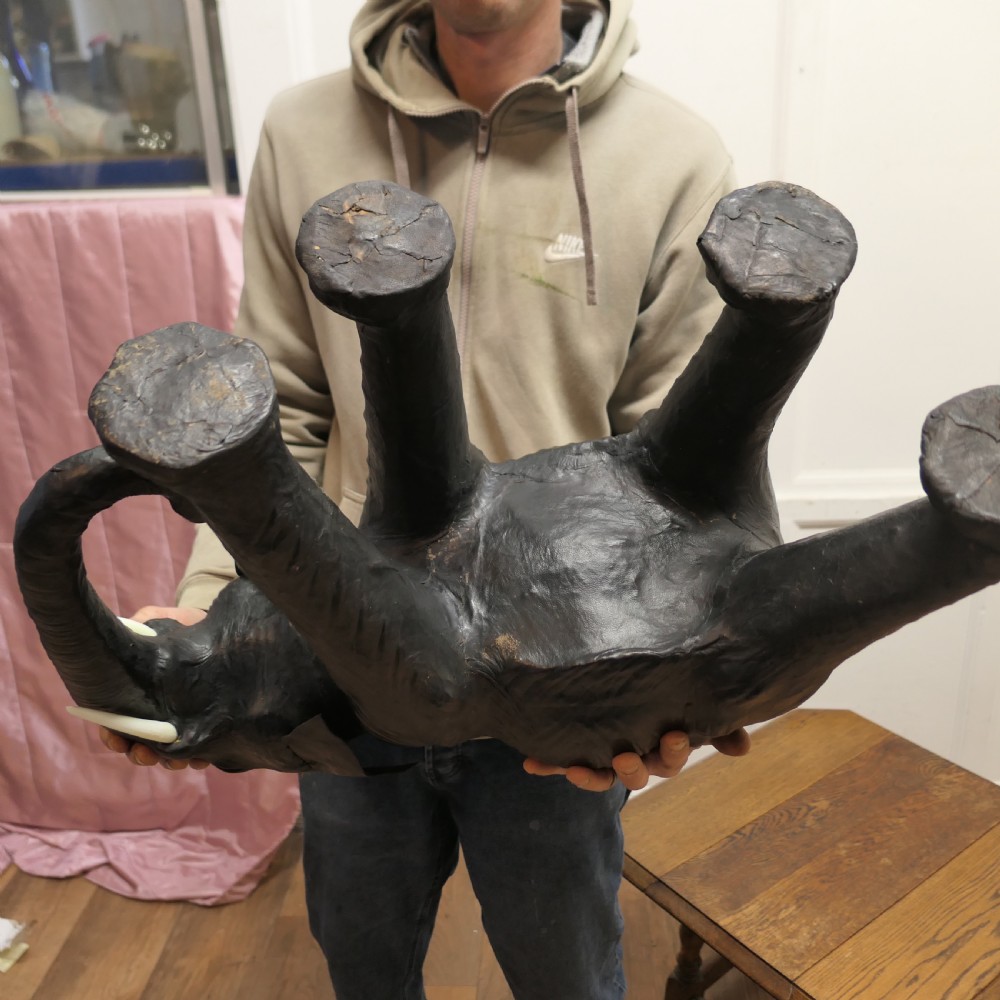 A dark brown moulded leather model of a standing bull elephant with realistic skin texture and light-coloured tusks. View XIII