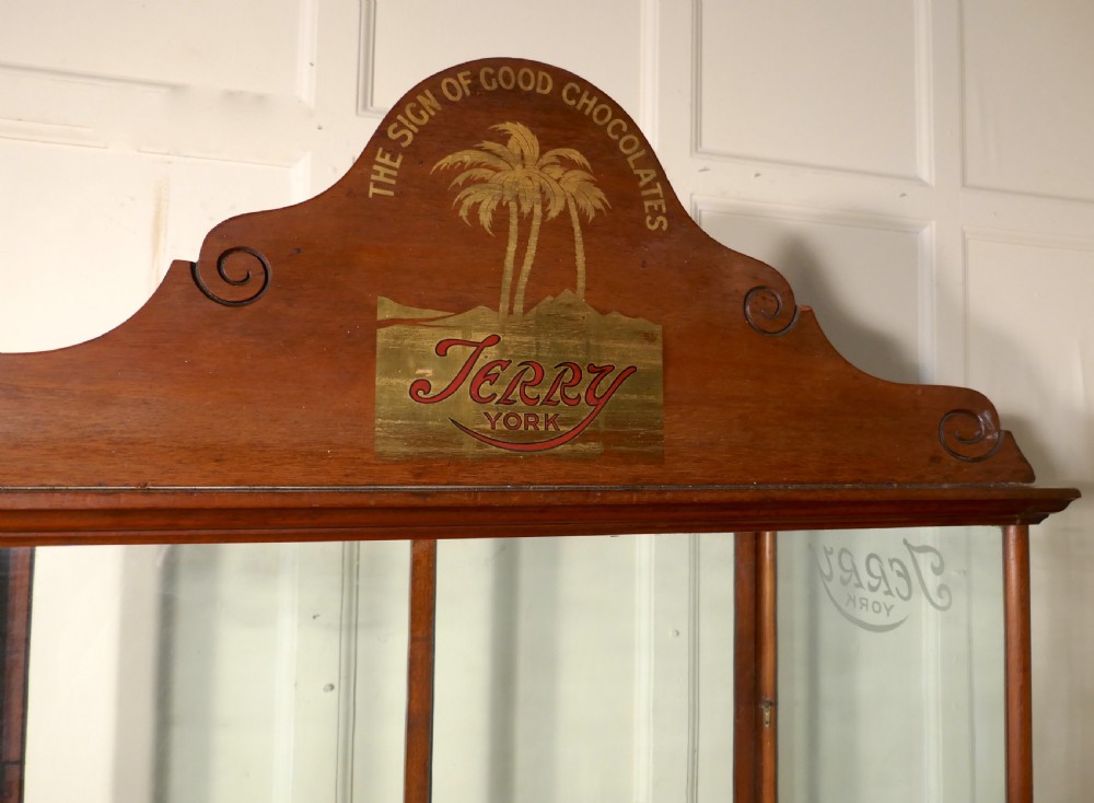 An antique mahogany glazed shop display cabinet with a pediment cresting featuring Terrys of York branding and etched glass panels. View V