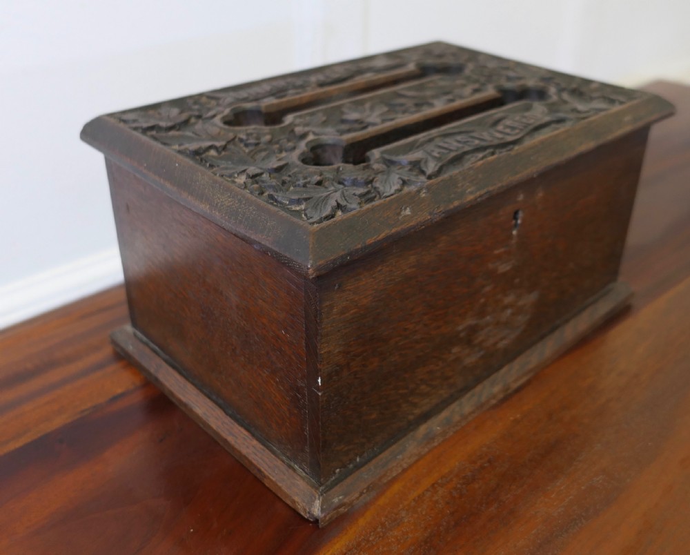 A dark carved oak correspondence box featuring a hinged lid with carved relief detail, a front keyhole, and a moulded rectangular base. View III