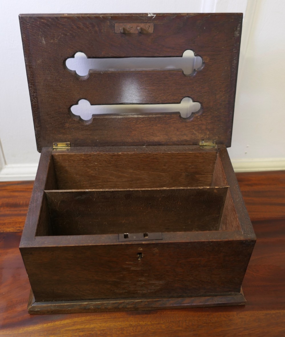 A dark carved oak correspondence box featuring a hinged lid with carved relief detail, a front keyhole, and a moulded rectangular base. View IV