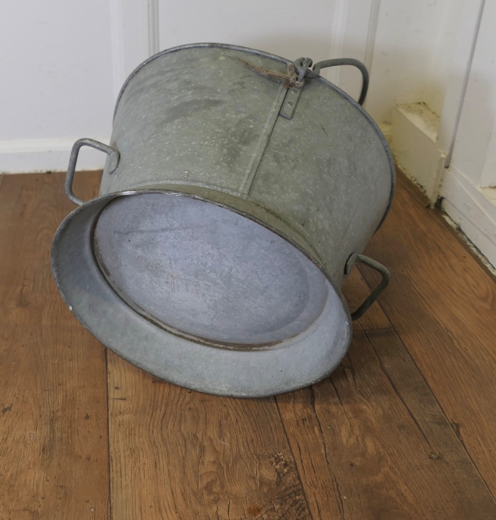 A large galvanised steel housemaid bucket featuring side drop handles, a swing bail handle, and a flared base. View IV