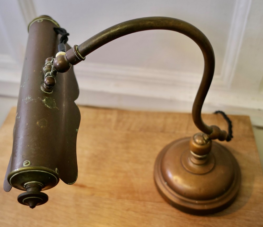 An antique brass desk lamp featuring a curved gooseneck stem, a circular weighted base, and an adjustable scalloped shade. View VIII