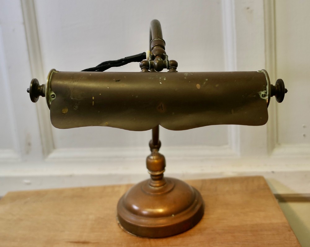 An antique brass desk lamp featuring a curved gooseneck stem, a circular weighted base, and an adjustable scalloped shade. View IX