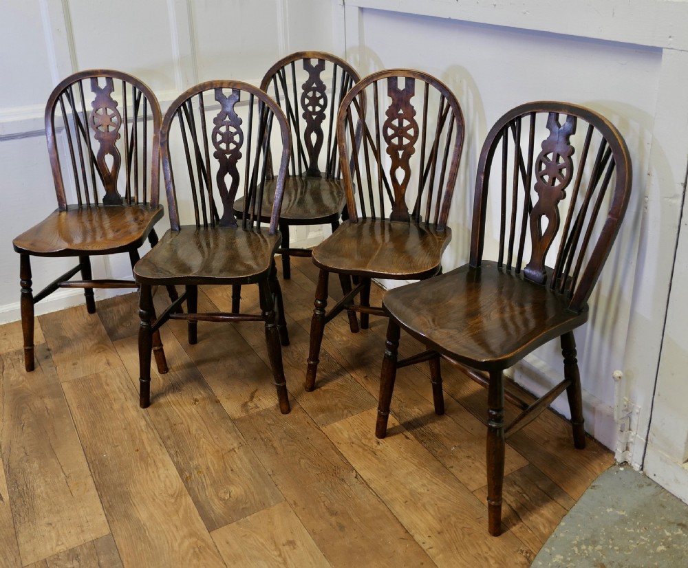 A set of five dark brown Victorian Windsor dining chairs with pierced wheelback central splats, hoop backs, and turned legs. View II