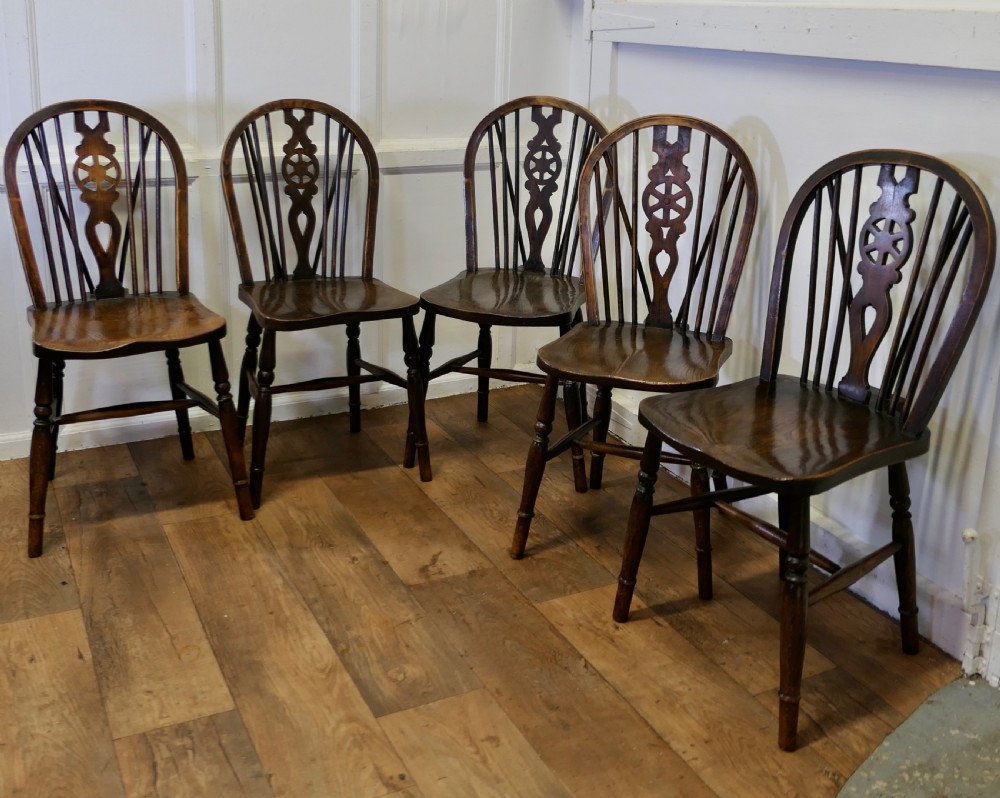 A set of five dark brown Victorian Windsor dining chairs with pierced wheelback central splats, hoop backs, and turned legs. View V