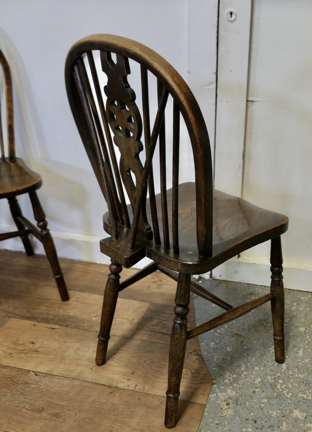 A set of five dark brown Victorian Windsor dining chairs with pierced wheelback central splats, hoop backs, and turned legs. View VI