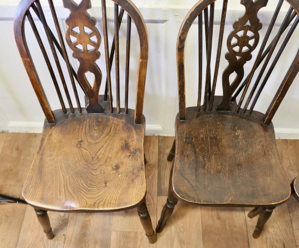 A set of five dark brown Victorian Windsor dining chairs with pierced wheelback central splats, hoop backs, and turned legs. View VII