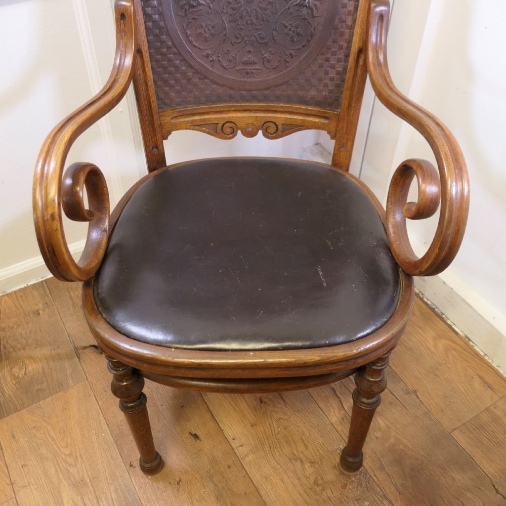 A Victorian bentwood armchair featuring a dark brown leather seat, scrolled armrests, turned front legs, and an embossed patterned back panel. View VI