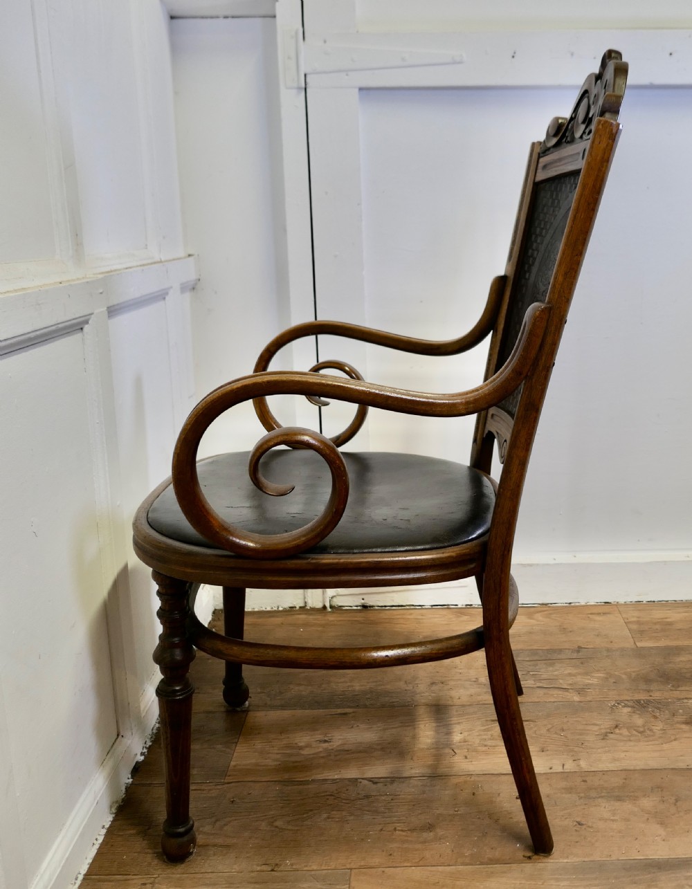 A Victorian bentwood armchair featuring a dark brown leather seat, scrolled armrests, turned front legs, and an embossed patterned back panel. View IX