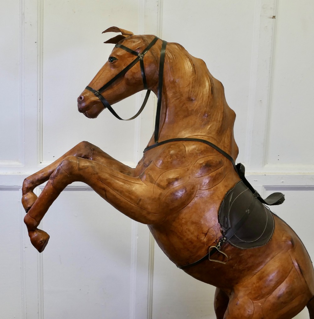 A life-size Arts and Crafts leather model of a rearing horse with dark leather bridle and saddle, mounted on a rustic wooden base. View III
