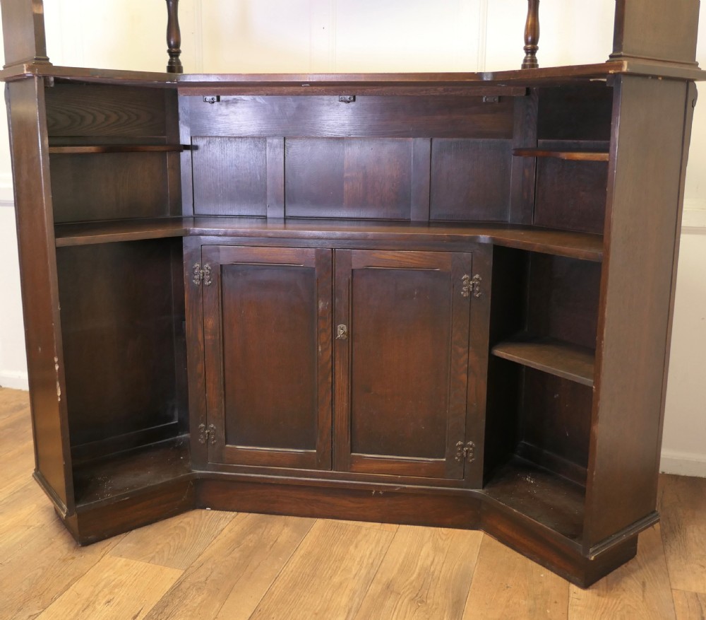 A dark brown carved oak canopy bar featuring turned spindle columns, open side shelves, an overhead frieze, and vertical panelled detailing on the base. View VIII