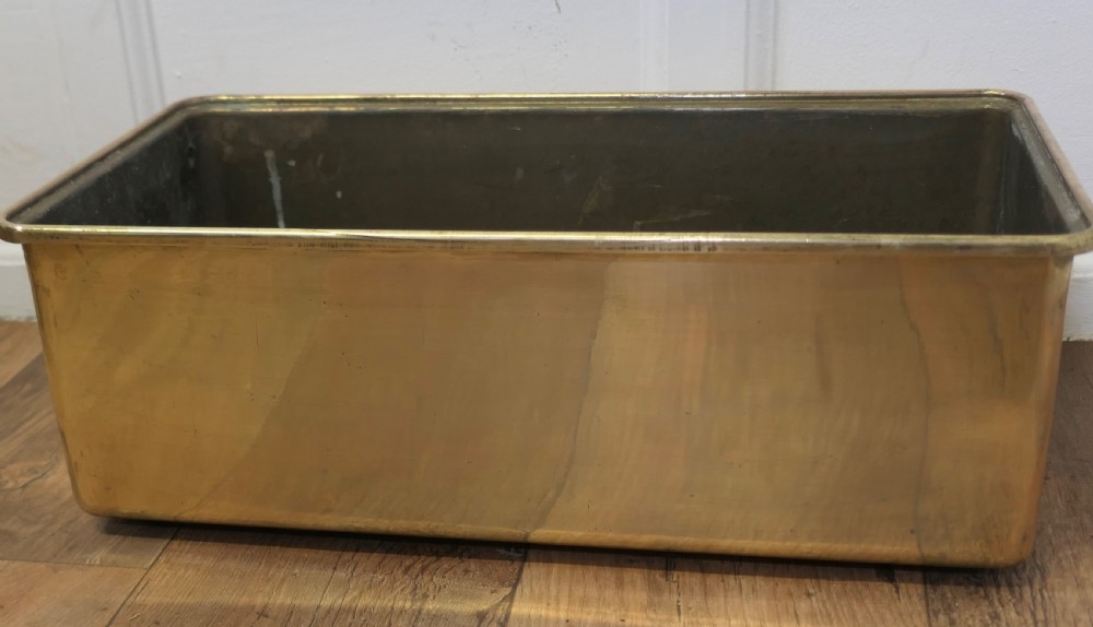 A heavy rectangular solid brass planter trough with rounded corners and a folded top rim. View V