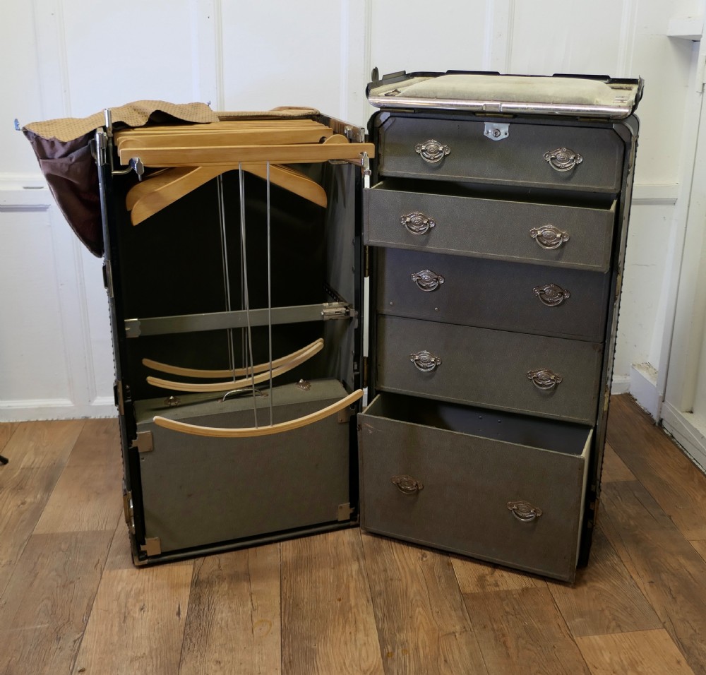 An open Art Deco Hartmann fitted steamer trunk featuring a section with wooden clothes hangers and a section with five pull-out drawers.