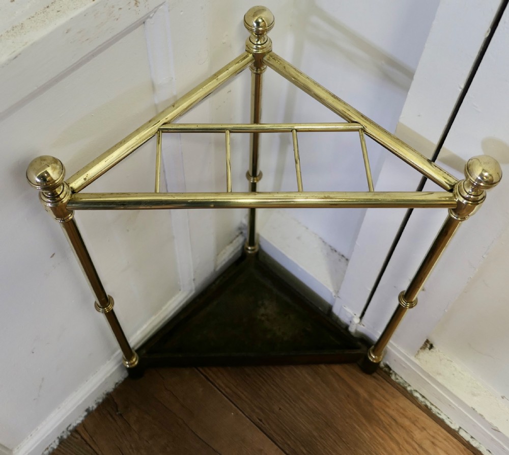 A Victorian corner umbrella stand featuring tubular brass uprights with turned ball finials and a heavy triangular cast iron drip tray at the base. View III
