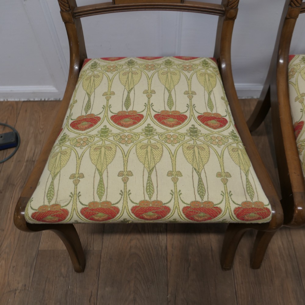 A set of four Art Nouveau walnut dining chairs featuring twisted top rails, inlaid back splats, and floral patterned fabric seats. View IV