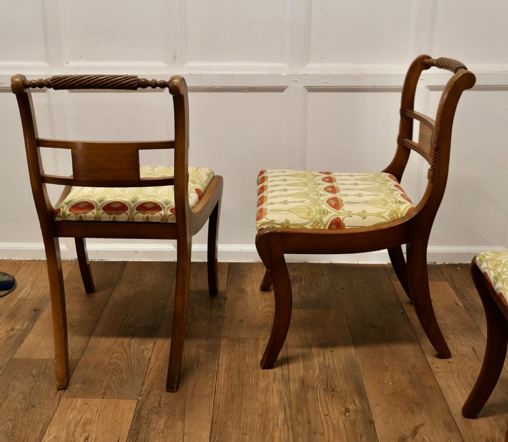 A set of four Art Nouveau walnut dining chairs featuring twisted top rails, inlaid back splats, and floral patterned fabric seats. View VI