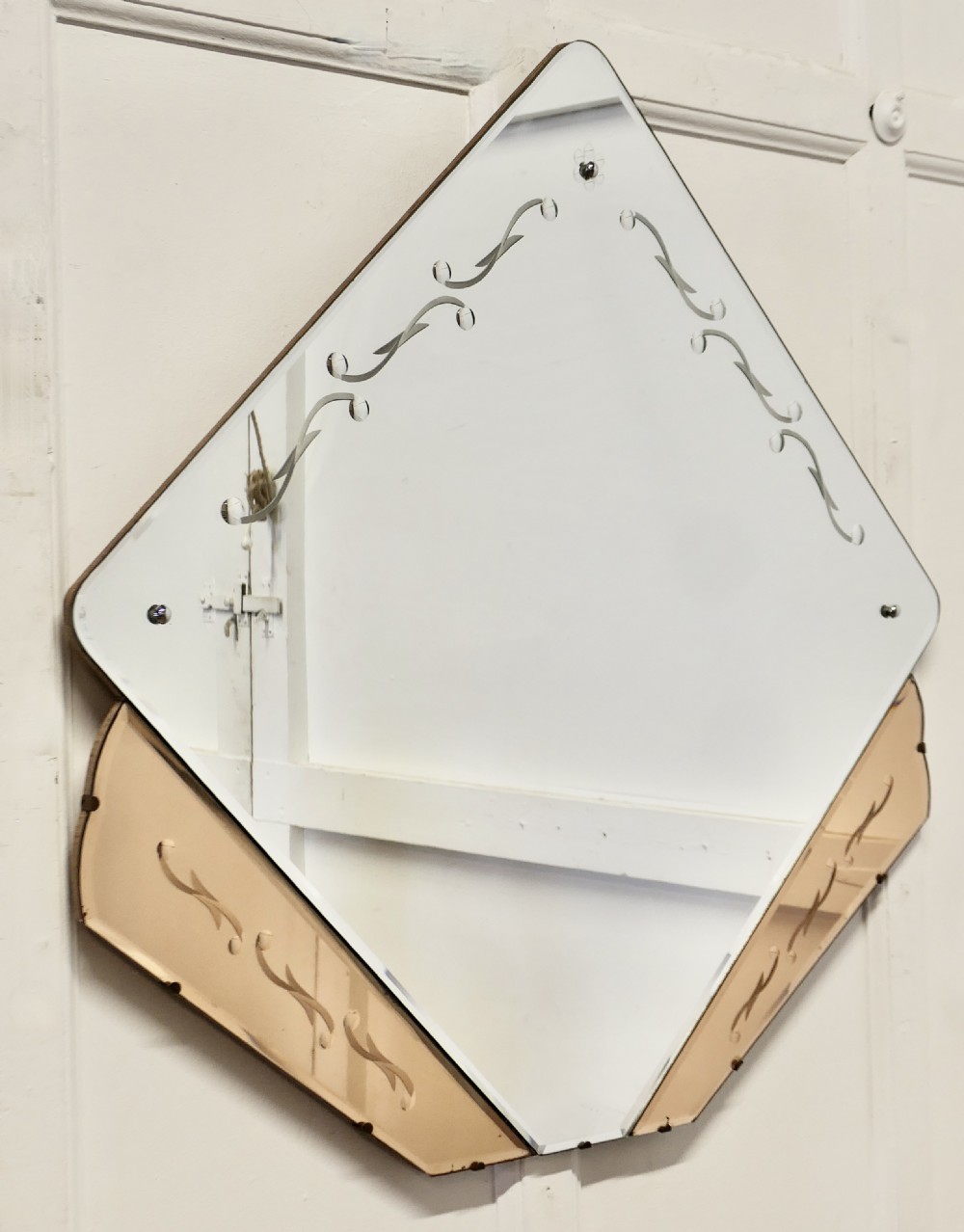 A diamond-shaped Art Deco wall mirror featuring a clear main glass panel with etched scroll motifs and angled peach-tinted glass lower borders.
