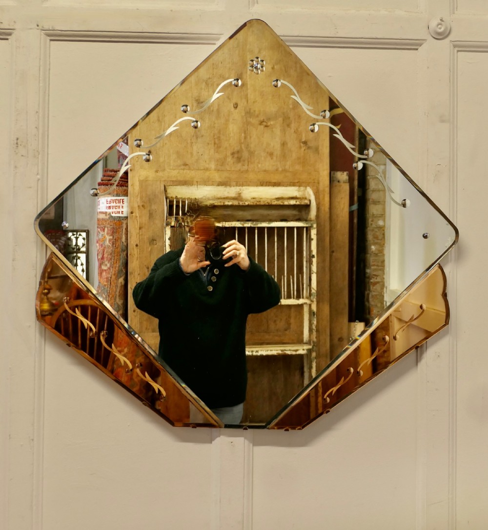 A diamond-shaped Art Deco wall mirror featuring a clear main glass panel with etched scroll motifs and angled peach-tinted glass lower borders. View II